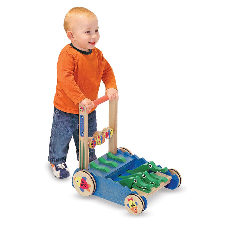 A child on white background with the Melissa & Doug Deluxe Chomp and Clack Alligator Wooden Push Toy and Activity Walker