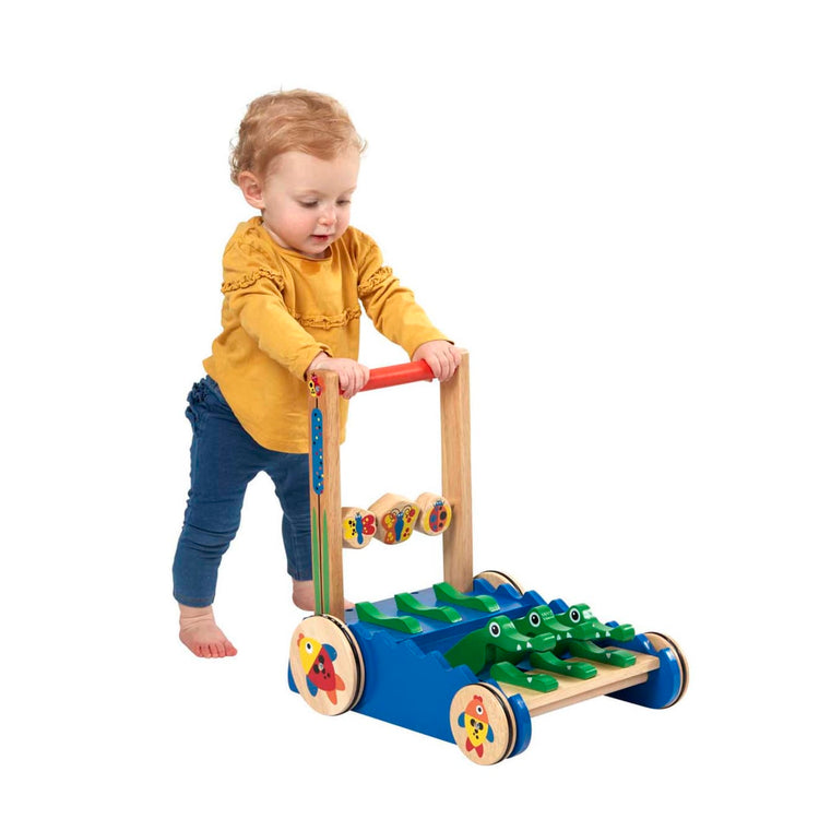 A child on white background with the Melissa & Doug Deluxe Chomp and Clack Alligator Wooden Push Toy and Activity Walker