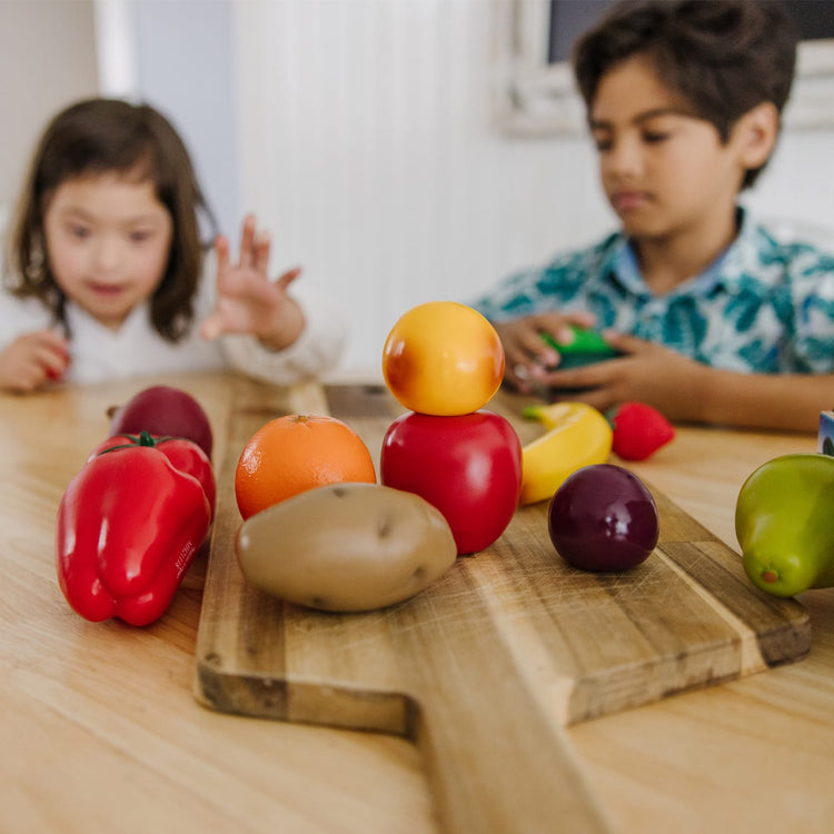 A kid playing with the Melissa & Doug Play-Time Produce Fruit (9 pcs) and Vegetables (7 pcs) Realistic Play Food