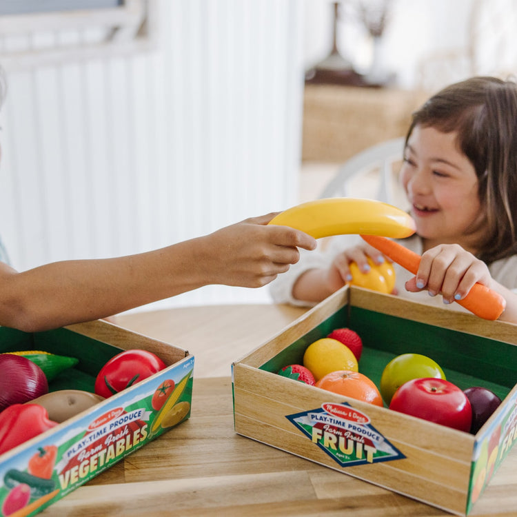 A kid playing with the Melissa & Doug Play-Time Produce Fruit (9 pcs) and Vegetables (7 pcs) Realistic Play Food