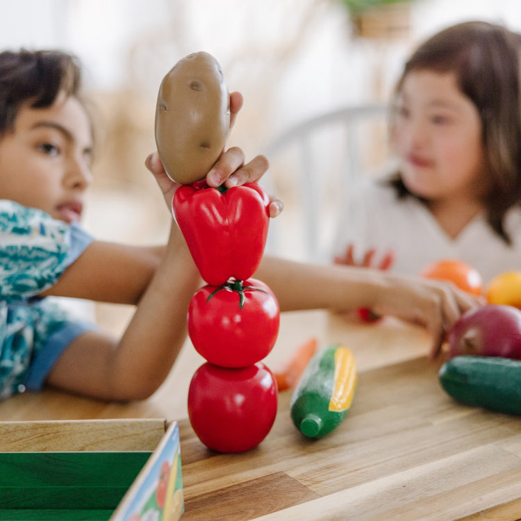 A kid playing with the Melissa & Doug Play-Time Produce Fruit (9 pcs) and Vegetables (7 pcs) Realistic Play Food