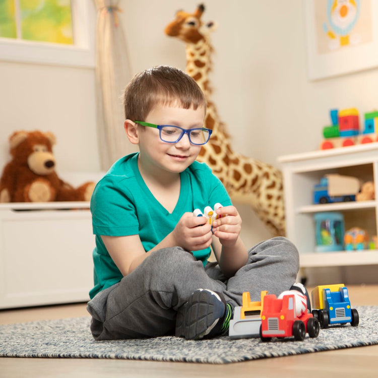 A kid playing with the Melissa & Doug Construction Vehicle Wooden Play Set (8 pcs)