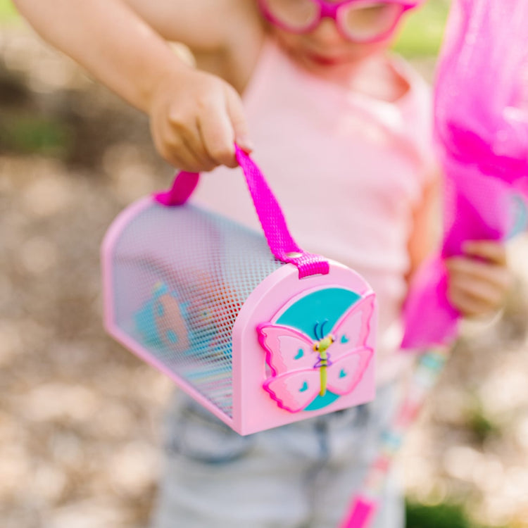 A kid playing with the Melissa & Doug Sunny Patch Cutie Pie Butterfly Bug House Toy With Carrying Handle and Easy-Access Door