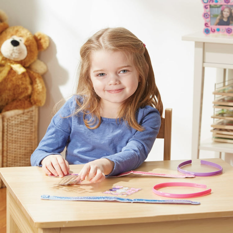 A kid playing with the Melissa & Doug Design-Your-Own Headbands Jewelry-Making Kit With 50+ Stickers