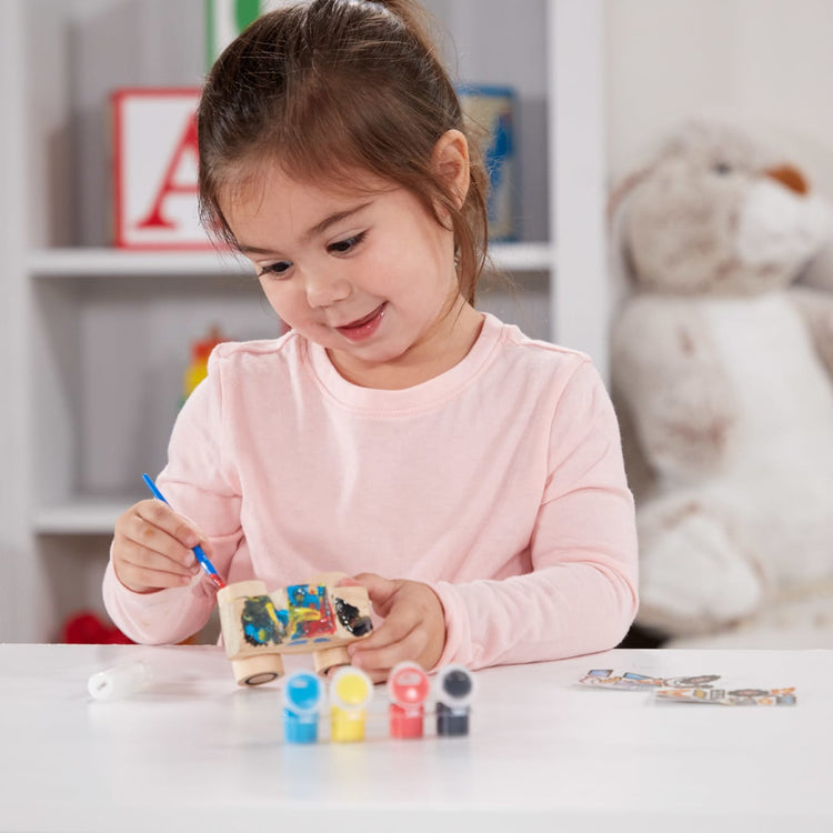 A kid playing with the Melissa & Doug Created by Me! Monster Truck Wooden Craft Kit