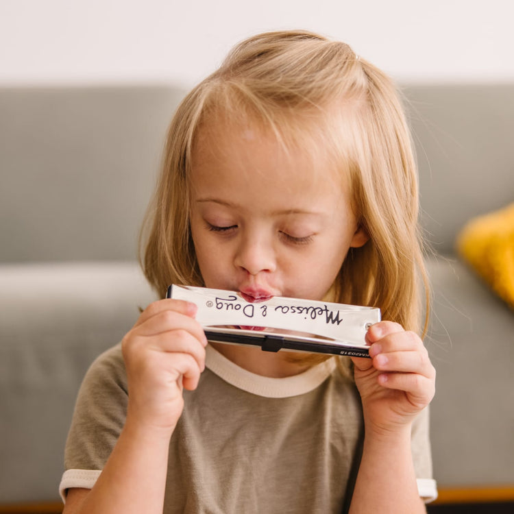 A kid playing with the Melissa & Doug Deluxe Band Set With Wooden Musical Instruments and Storage Case