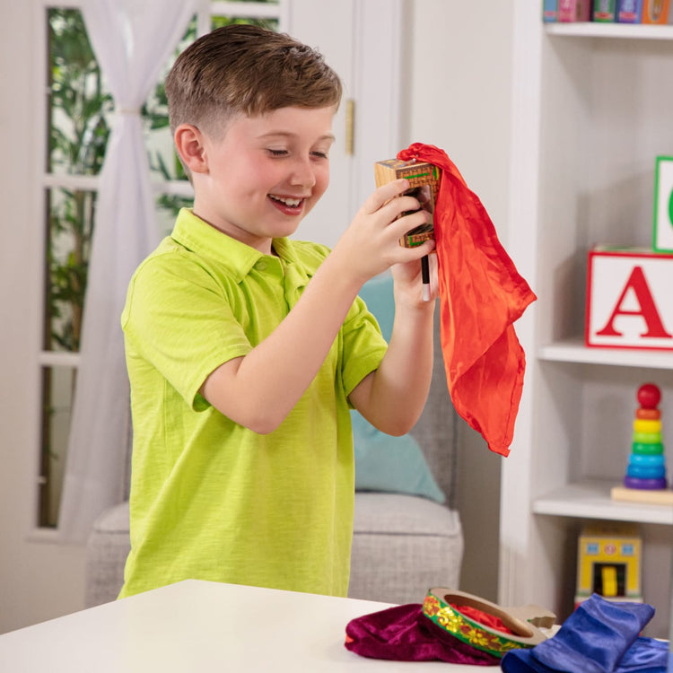 A kid playing with the Melissa & Doug Deluxe Solid-Wood Magic Set With 10 Classic Tricks