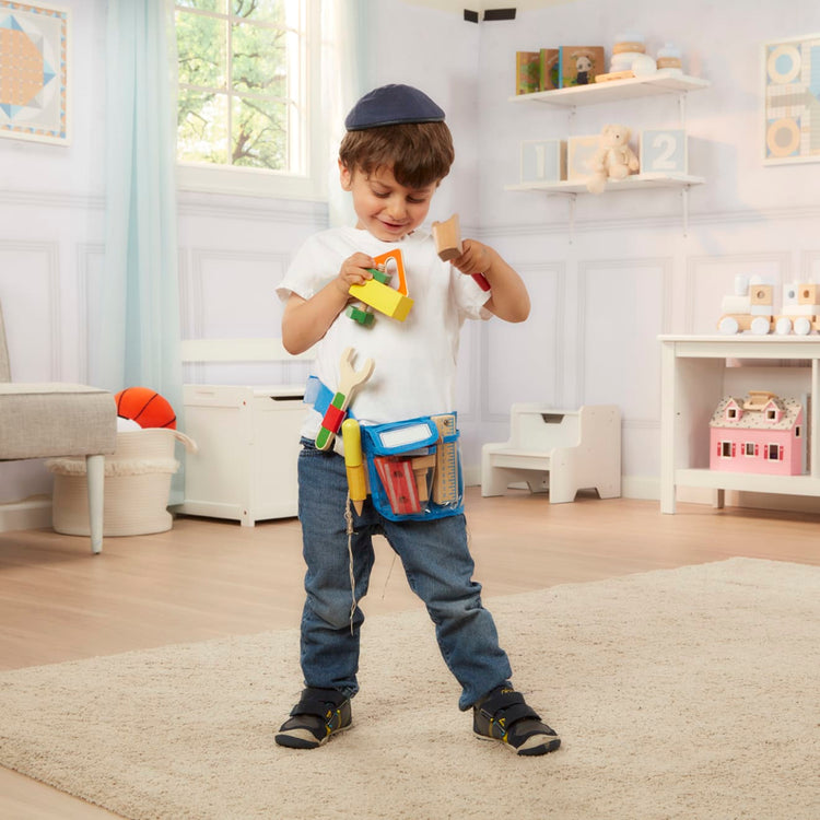 A kid playing with the Melissa & Doug Deluxe Tool Belt Set - 5 Wooden Tools, 8 Building Pieces, Adjustable Belt