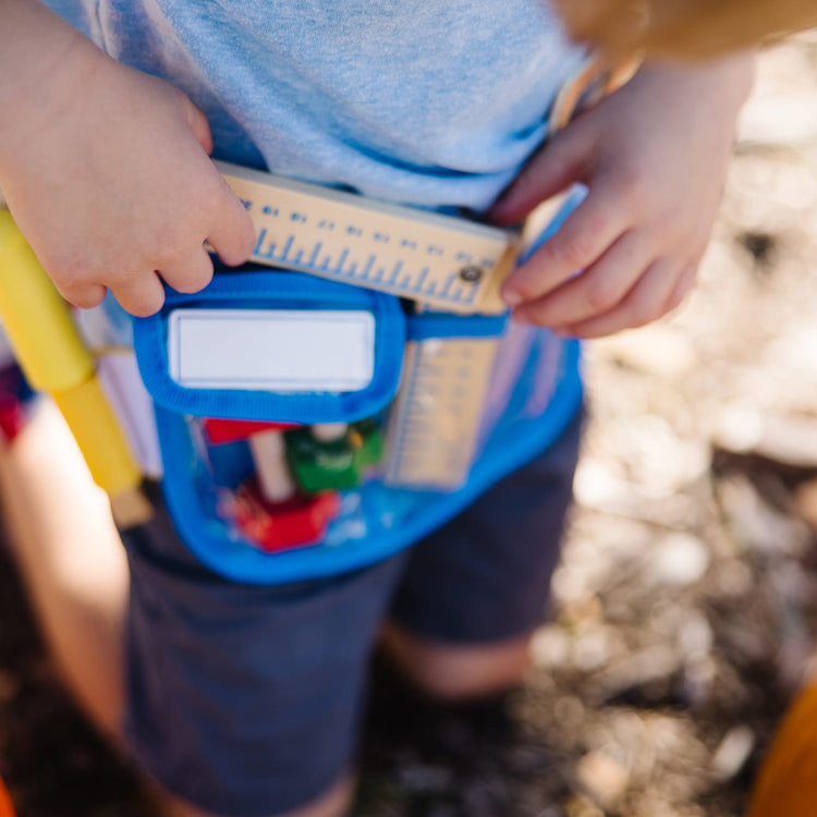 A kid playing with the Melissa & Doug Deluxe Tool Belt Set - 5 Wooden Tools, 8 Building Pieces, Adjustable Belt