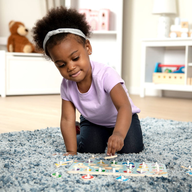 A kid playing with the Melissa & Doug Disney Classics Alphabet Wooden Peg Puzzle (26 pcs)