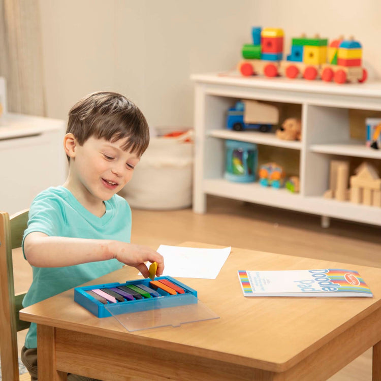 A kid playing with the Melissa & Doug Doodle Pad (6 x 9 inches) With 50 Sheets of White Bond Paper