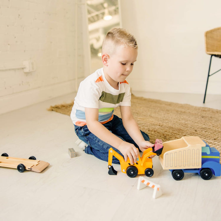 A kid playing with the Melissa & Doug Classic Toy Wooden Dump Truck & Loader with Construction Pieces