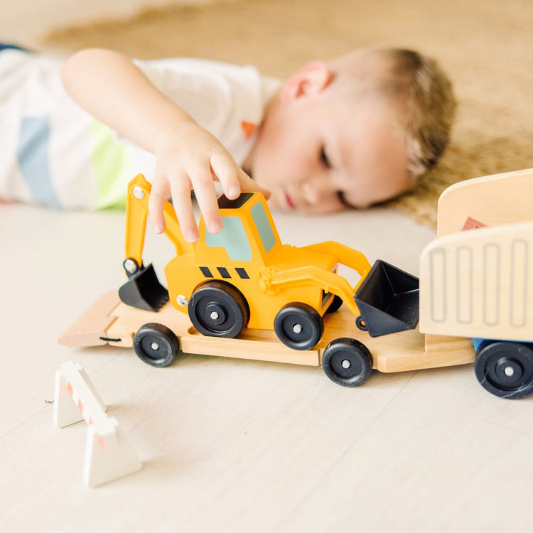 A kid playing with the Melissa & Doug Classic Toy Wooden Dump Truck & Loader with Construction Pieces