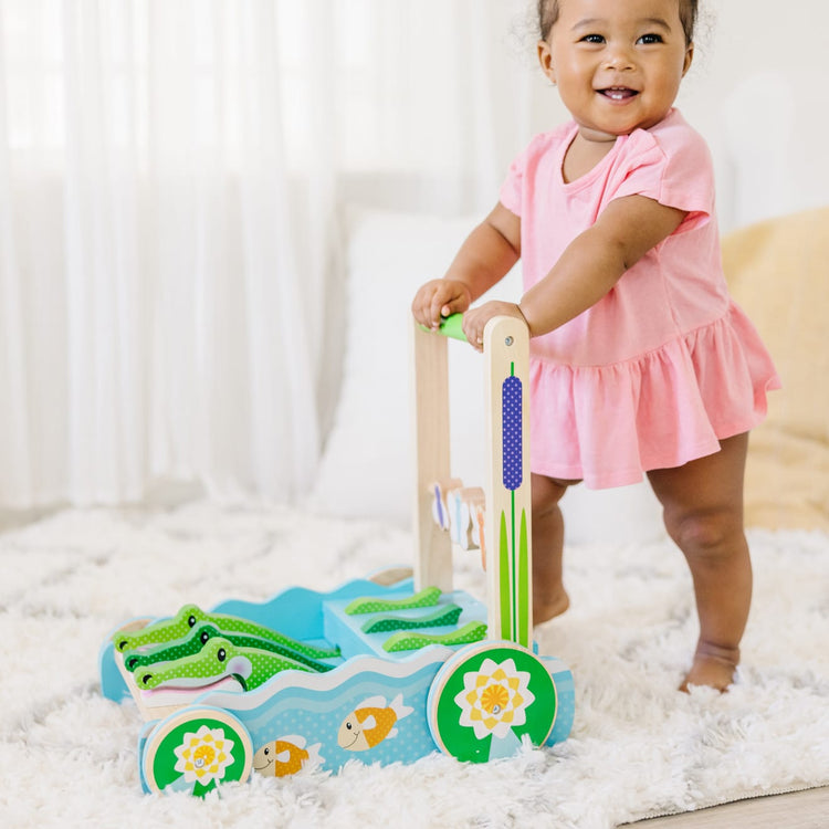 A kid playing with the Melissa & Doug First Play Chomp and Clack Alligator Wooden Push Toy and Activity Walker