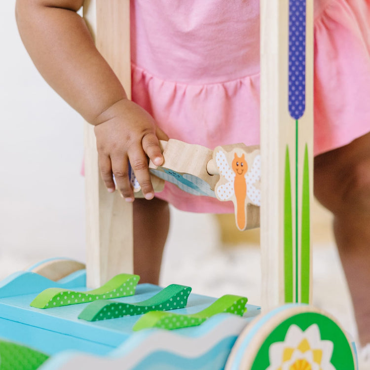 A kid playing with the Melissa & Doug First Play Chomp and Clack Alligator Wooden Push Toy and Activity Walker