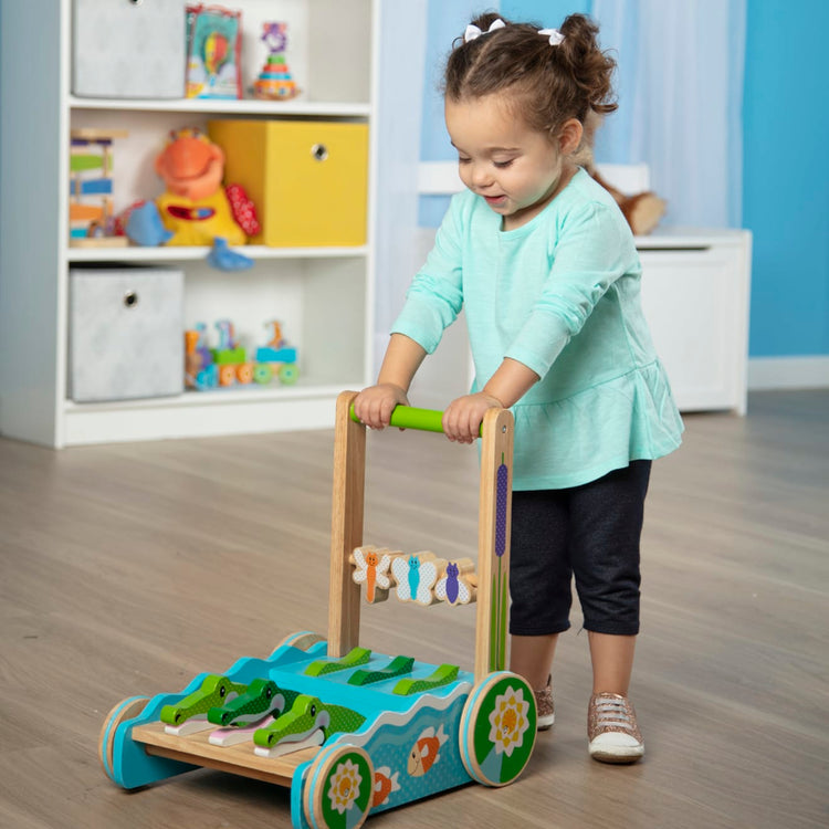 A kid playing with the Melissa & Doug First Play Chomp and Clack Alligator Wooden Push Toy and Activity Walker