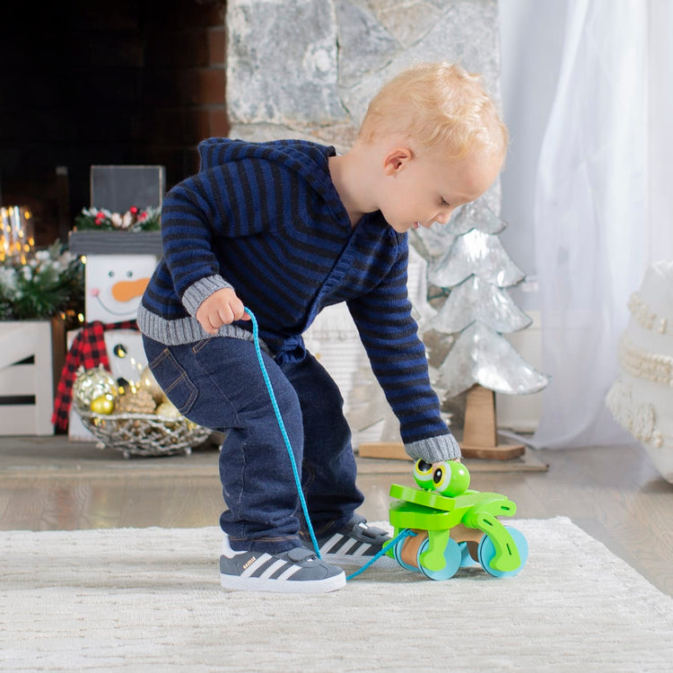 A kid playing with the Melissa & Doug First Play Frolicking Frog Wooden Pull Toy