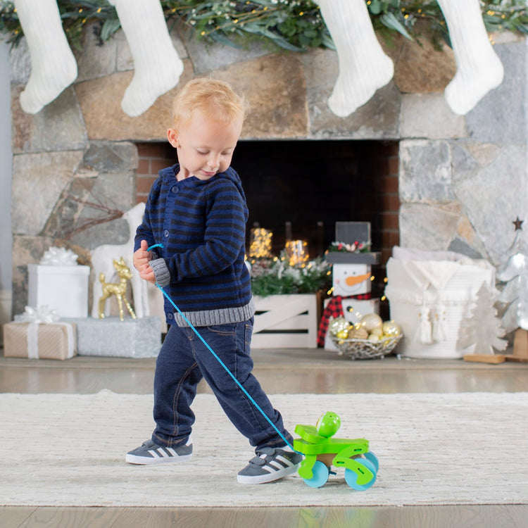 A kid playing with the Melissa & Doug First Play Frolicking Frog Wooden Pull Toy