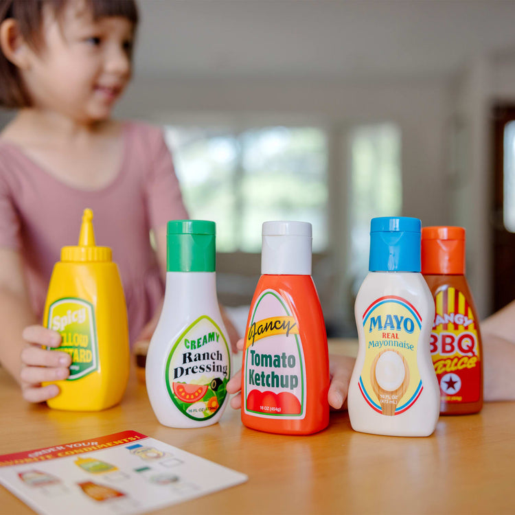 A kid playing with the Melissa & Doug 5-Piece Favorite Condiments Play Food Set