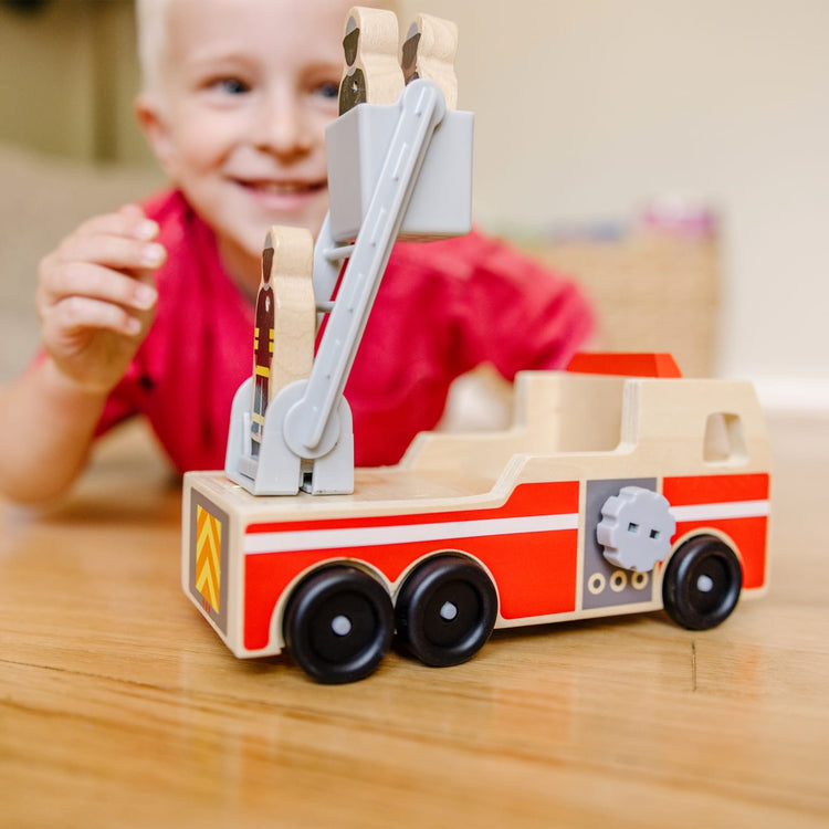 A kid playing with the Melissa & Doug Wooden Fire Truck With 3 Firefighter Play Figures