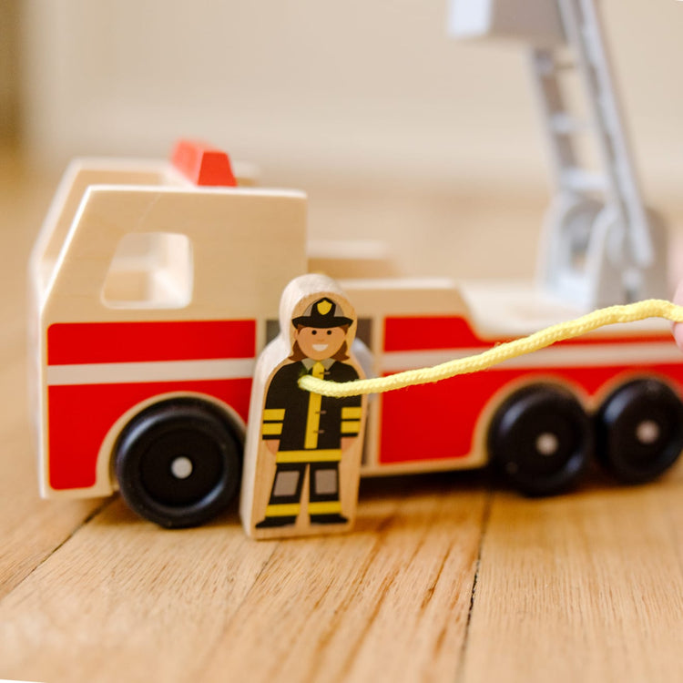 A kid playing with the Melissa & Doug Wooden Fire Truck With 3 Firefighter Play Figures