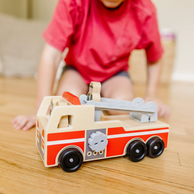 A kid playing with the Melissa & Doug Wooden Fire Truck With 3 Firefighter Play Figures