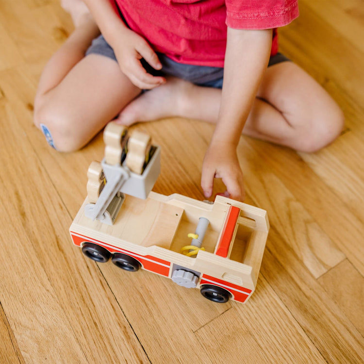 A kid playing with the Melissa & Doug Wooden Fire Truck With 3 Firefighter Play Figures