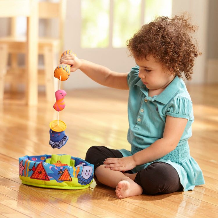 A kid playing with the Melissa & Doug K's Kids Fish and Count Learning Game With 8 Numbered Fish to Catch and Release