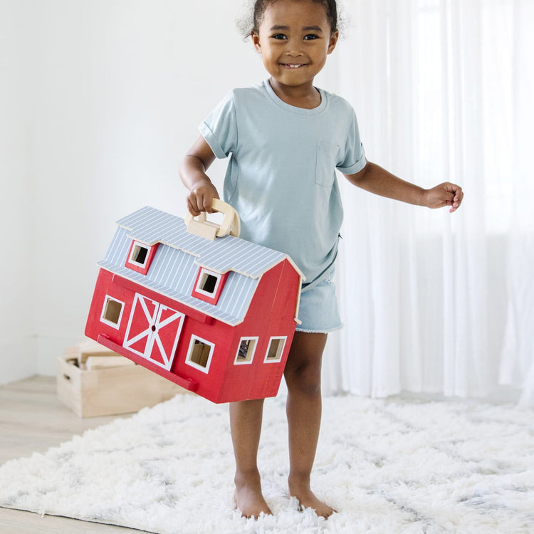 A kid playing with the Melissa & Doug Fold and Go Wooden Barn With 7 Animal Play Figures