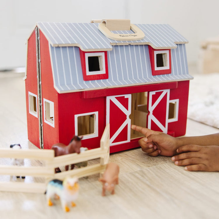 A kid playing with the Melissa & Doug Fold and Go Wooden Barn With 7 Animal Play Figures