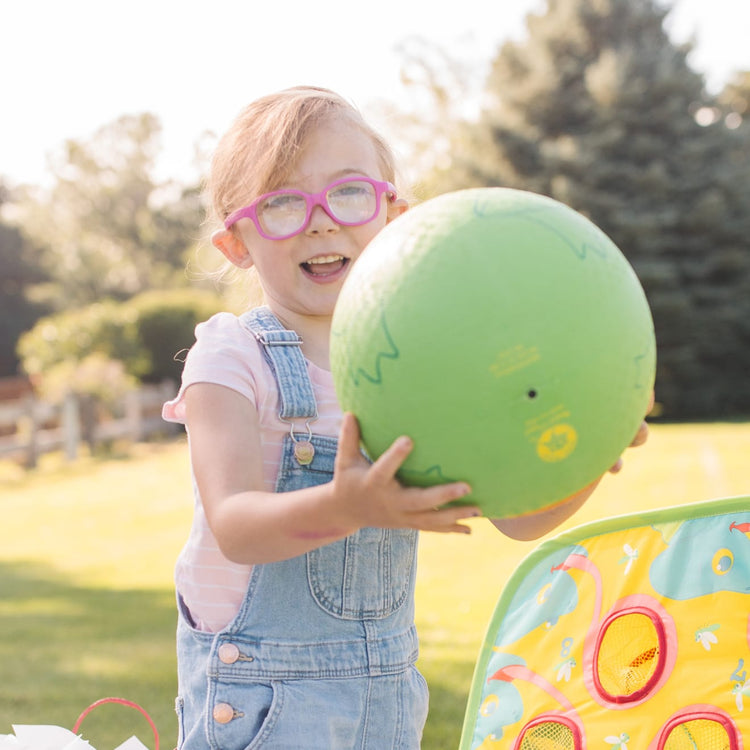 A kid playing with the Melissa & Doug Sunny Patch Froggy Classic Rubber Kickball