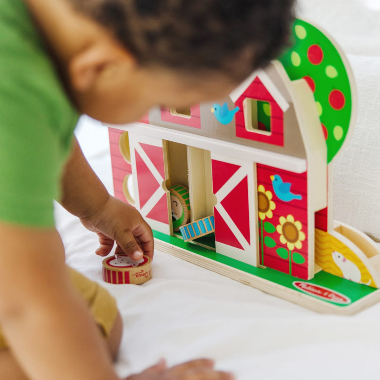 A kid playing with the Melissa & Doug GO Tots Wooden Barnyard Tumble with 4 Disks