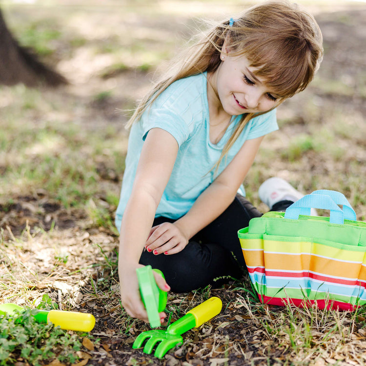 A kid playing with the Melissa & Doug Sunny Patch Giddy Buggy Toy Gardening Tote Set With Tools