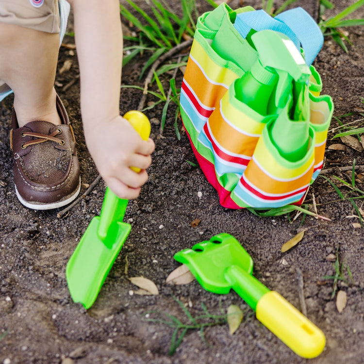 A kid playing with the Melissa & Doug Sunny Patch Giddy Buggy Toy Gardening Tote Set With Tools