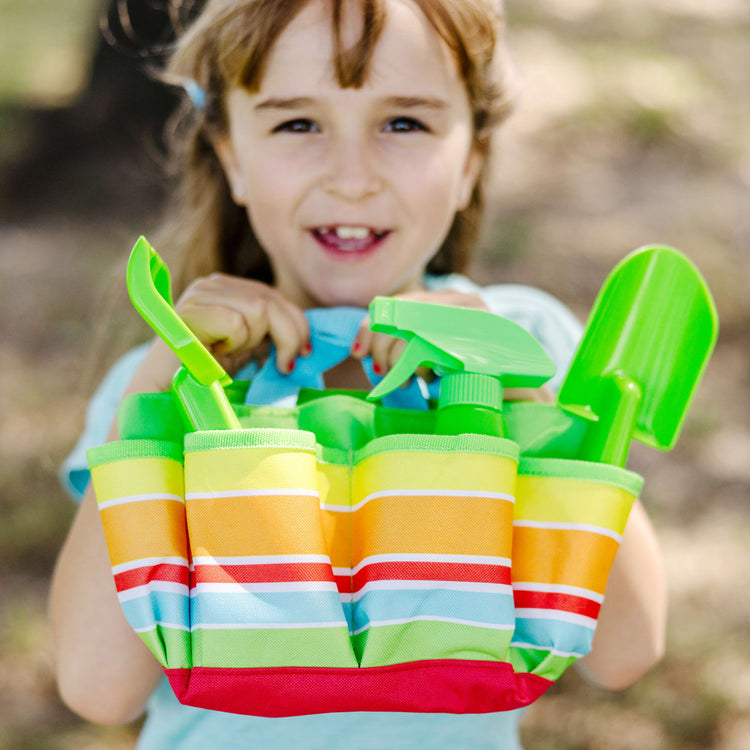 A kid playing with the Melissa & Doug Sunny Patch Giddy Buggy Toy Gardening Tote Set With Tools