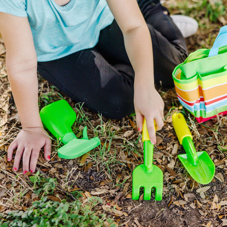 A kid playing with the Melissa & Doug Sunny Patch Giddy Buggy Toy Gardening Tote Set With Tools