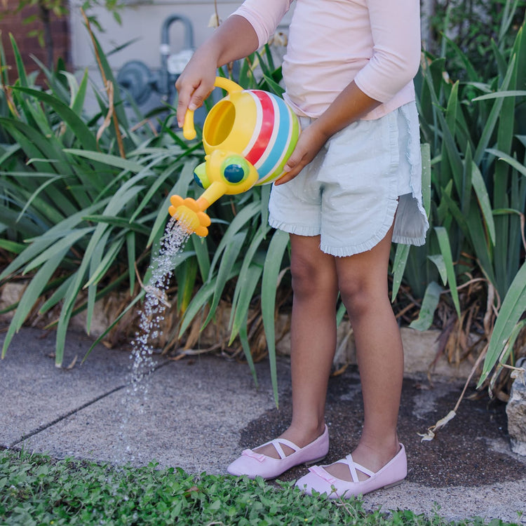 A kid playing with the Melissa & Doug Sunny Patch Giddy Buggy Watering Can With Flower-Shaped Spout