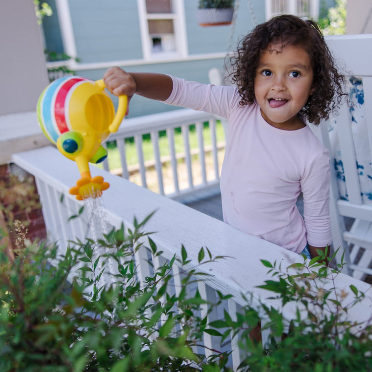 A kid playing with the Melissa & Doug Sunny Patch Giddy Buggy Watering Can With Flower-Shaped Spout