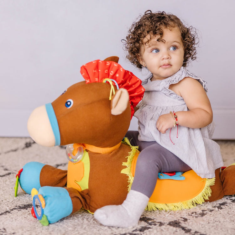 A kid playing with the Melissa & Doug Giddy-Up and Play Baby Activity Toy - Multi-Sensory Horse