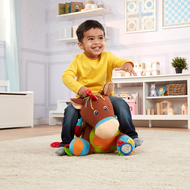 A kid playing with the Melissa & Doug Giddy-Up and Play Baby Activity Toy - Multi-Sensory Horse