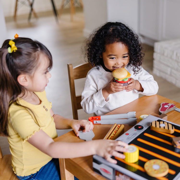 A kid playing with the Melissa & Doug Grill and Serve BBQ Set (20 pcs) - Wooden Play Food and Accessories