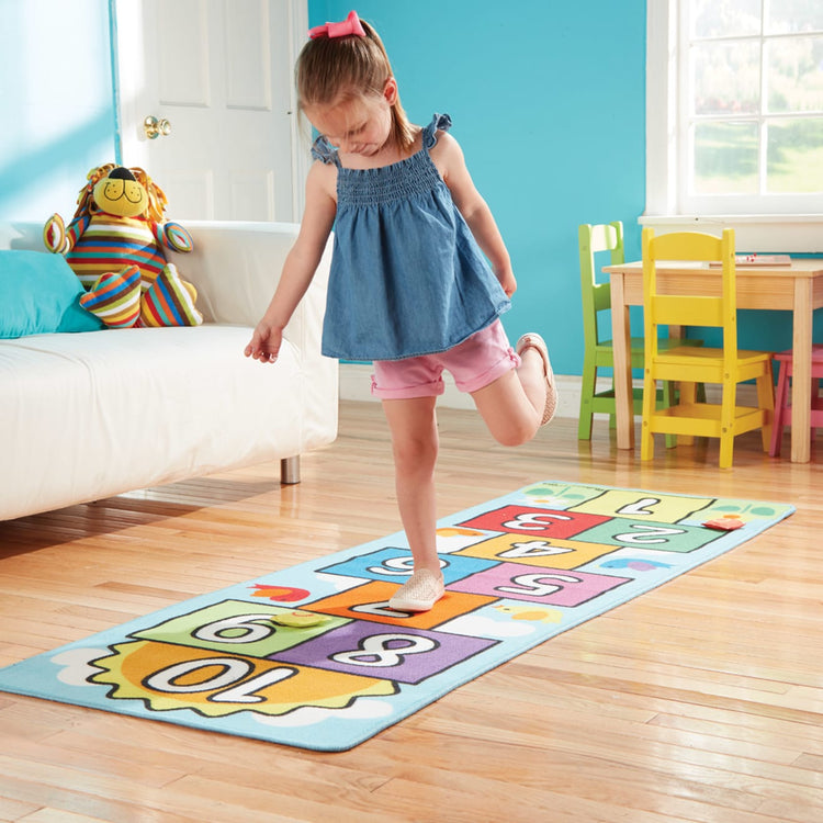 A kid playing with the Melissa & Doug Hop and Count Hopscotch Game Rug  (3 pcs, 78.5 x 26.5 inches)