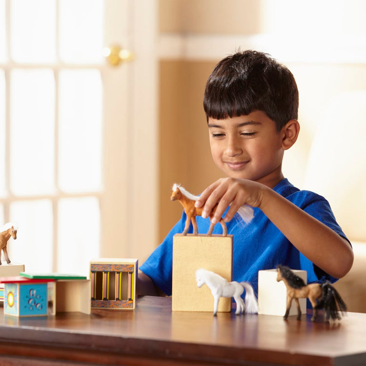 A kid playing with the Melissa & Doug Horse Carrier Wooden Vehicle Play Set With 2 Flocked Horses and Pull-Down Ramp