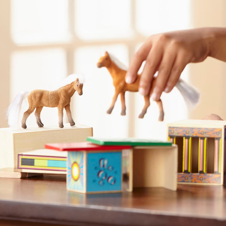 A kid playing with the Melissa & Doug Horse Carrier Wooden Vehicle Play Set With 2 Flocked Horses and Pull-Down Ramp