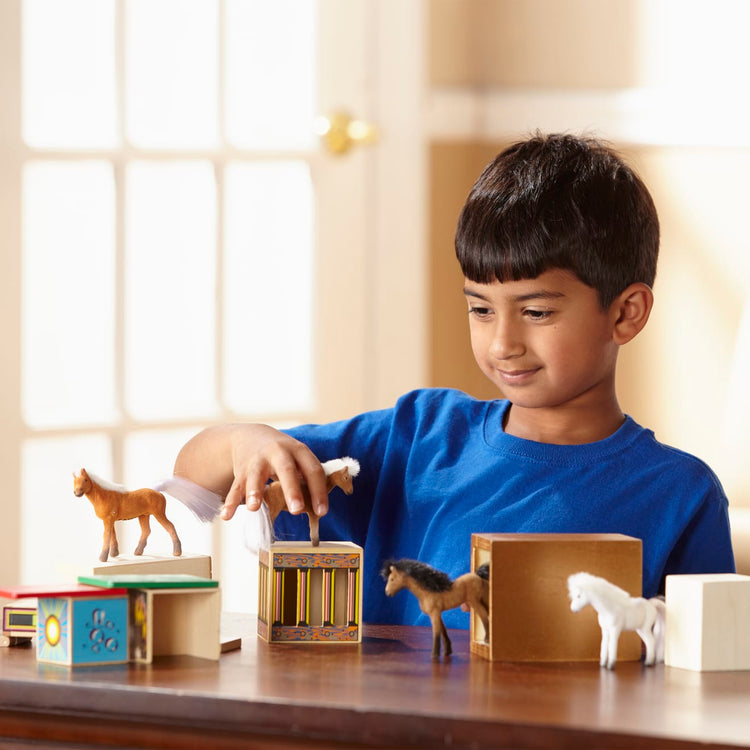 A kid playing with the Melissa & Doug Horse Carrier Wooden Vehicle Play Set With 2 Flocked Horses and Pull-Down Ramp