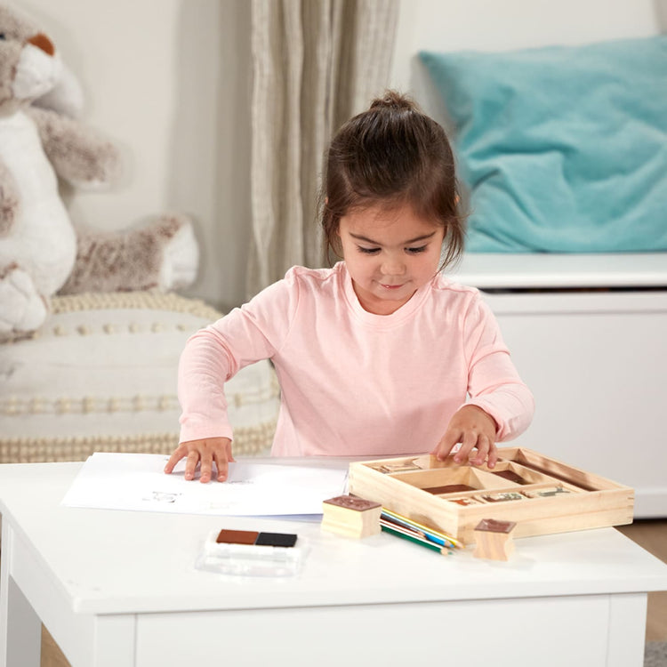 A kid playing with the Melissa & Doug Wooden Stamp Activity Set: Horses - 10 Stamps, 5 Colored Pencils, 2-Color Stamp Pad