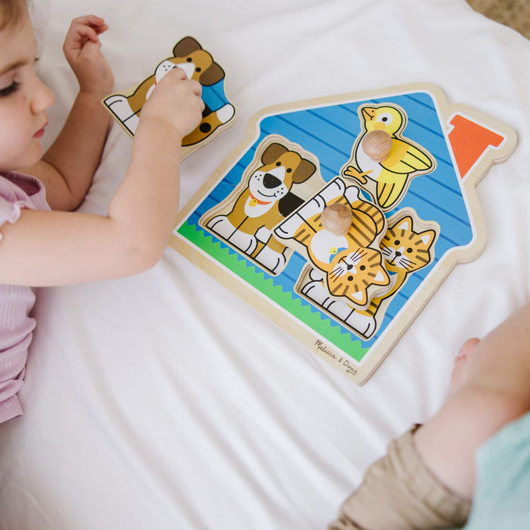 A kid playing with the Melissa & Doug Pets Jumbo Knob Wooden Puzzle