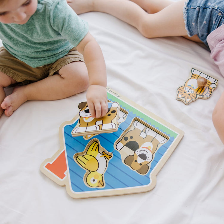 A kid playing with the Melissa & Doug Pets Jumbo Knob Wooden Puzzle