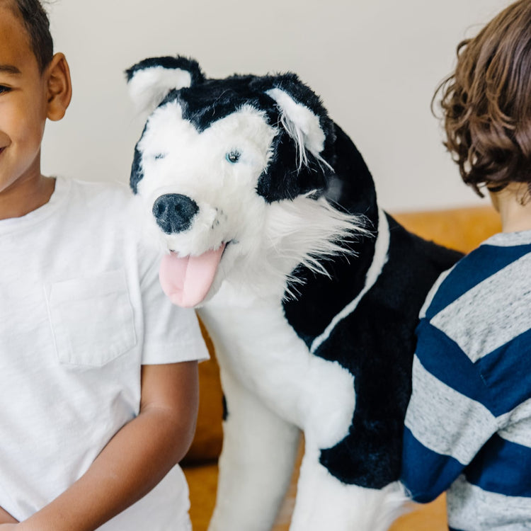 A kid playing with the Melissa & Doug Giant Siberian Husky - Lifelike Stuffed Animal Dog (over 2 feet tall)