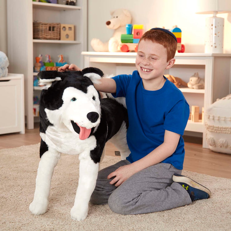 A kid playing with the Melissa & Doug Giant Siberian Husky - Lifelike Stuffed Animal Dog (over 2 feet tall)